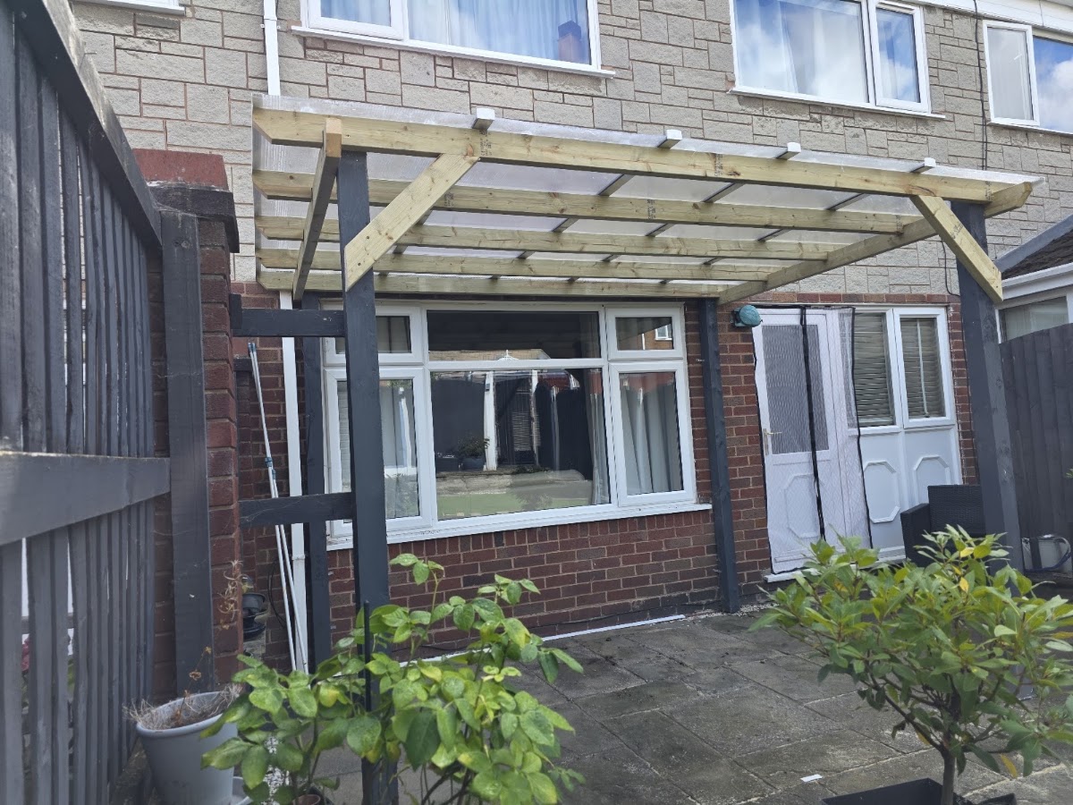 A polycarbonate-roofed timber canopy against a house